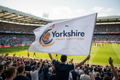 Custom printed football flag with Yorkshire Print Solutions branding being waved in a stadium